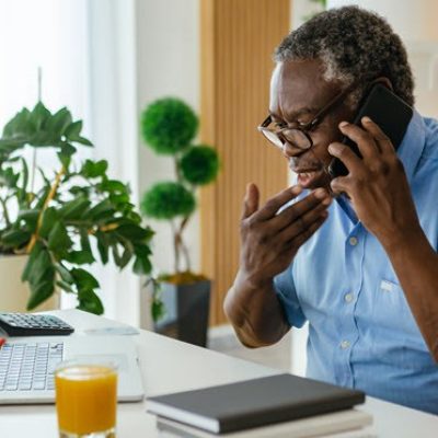 Man in front of laptop on the phone with concern.