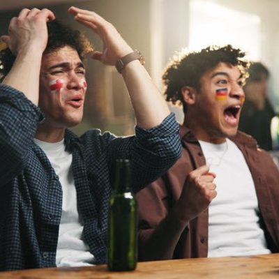 Two people rooting for opposing teams in a sports game.