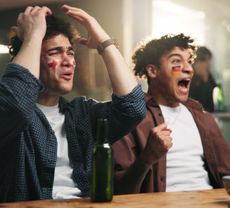 Two people rooting for opposing teams in a sports game.